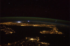 Noční Středozemní moře se vzdálenou bouřkou - povšimněte si hvězdokupy Plejády nad horizontem.