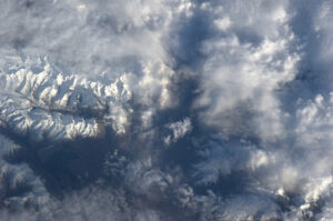 Nad mraky vykukují jen nejvyšší, sněhem zakryté vrcholky hor na Novém Zélandu.