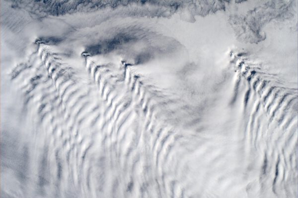 Jako když lodě svými příděmi rozráží vodu vypadají vrcholky sopek na Aleutských ostrovech, které čeří mraky.
