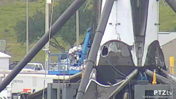 Falcon 9 přesunutý na zem a technici z něj právě odčerpávají provozní látky