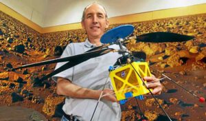 Matthew Golombek z JPL drží v rukou plnorozměrový model projektu Mars Helicopter.