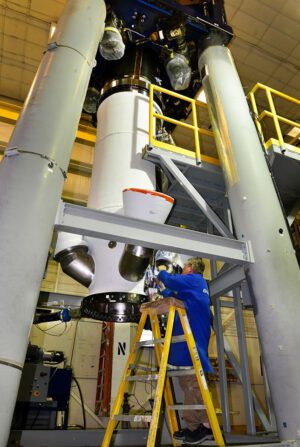Technik připravuje testovací exeplář záchranné věžičky lodi Orion - všimněte si „výfuků“ nad jeho hlavou.