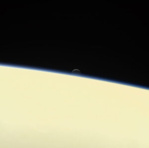 Saturnův aktivní a oceánem disponující měsíc Enceladus se schovává za obří planetou na rozlučkovém snímku mezinárodní sondy Cassini. Snímek vznikl 13. září společně s několika dalšími fotkami. Sonda k němu použila svou kameru s úzkým zorným polem a nasnímala Enceladus ze vzdálenosti 1,3 milionu kilometrů, přičemž Saturn byl 1 milion kilometrů daleko. Rozlišení na povrchu Enceladu je 8 km/pixel a snímek vznikl složením fotek pořízených přes červený, zelený a modrý filtr, aby bylo dosaženo přirozených barev. Projekt Cassini-Huygens byl společným podnikem NASA,ESA a Italské kosmické agentury.