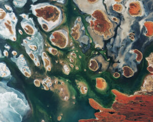 Hnědé kopce doplňují satelitní snímek východoaustralského jezera Lake MacKay. Nachází se na hranicích států Západní Austrálie a Severní Teritorium. Jedná se o solné jezero, které má vodu pouze po období dešťů a to navíc jen někdy. K tomu, aby se v něm udržela voda, potřebuje srážky, čímž se liší od sezónních jezer, která udrží vodu déle. Téměř polovina australských jezer ústí do vnitrozemí a často končí v takovýchto jezerech. Zelené a modré barvy na snímku ukazují rozložení řas, vlhkých půd a minerálů (většinou soli). Na některých hnědých „ostrovech“ a na pobřeží vpravo dole můžeme vidět písečné pruhy v západně-východním směru. Jezero leží na okraji Velké písečné pouště, která pokrývá 285 tisíc kilometrů čtverečních. Silnice jsou v této oblasti vzácné a nejčastěji je využívají dobrodruzi na čtyřkolkách. Mezi hlavní silnice patří Canning Stock Route, která leží zhruba 300 kilometrů západně od snímku, nebo Tanami Track, která spojuje Stuart Highway s Great Northern Highway a leží zhruba 300 kilometrů východně. Snímek zachytila 15. března družice Sentinel 2B. V té době byla stále v kalibrační fázi (od startu uplynulo jen 8 dní), ale přístroje již posílaly první fotky a ukazovaly své schopnosti snímkování pevniny, pobřeží a jezer. Po plném zprovoznění byly tyto prostředky zdarma zveřejněny pro široké spektrum uživatelů.