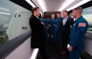 Elon Musk, administrátor NASA Jim Bridenstine a čtyři astronauti před startem Crew Dragonu v interiéru přístupové lávky do lodě.