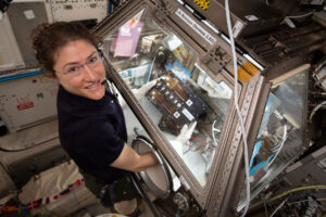 Christina Koch při práci s gloveboxem na ISS.