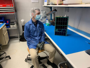 Hlavní vědekcý pracovník projektu CuPID,Brian Walsh, u dokončeného CubeSatu CuPID v červenci 2021 pouhý den před jeho usazením do vypouštěcího zařízení.