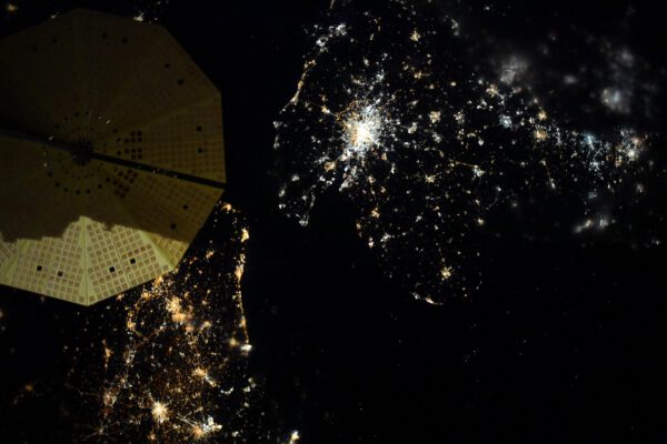 Neobvykle nasvícený solární panel nákladní lodi Cygnus (světlo odražené od Měsíce) v kombinaci se světly dole v Belgii a Anglii. Zdroj: flickr.com