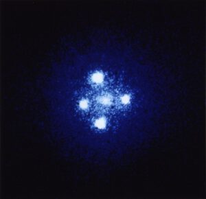 Einsteinův kříž v souhvězdí Pegase, jeden z nejznáměnších příkladů gravitačního čočkování. Uprostřed se nachází čočkující galaxie ZW 2237+030 ležící ve vzdálenosti asi 400 milionů světelných let, zatímco čočkovaný kvasar Q2237+030 nalézající se ve vzdálenosti 8 miliard světelných let vytváří čtyřnásobný obraz. 