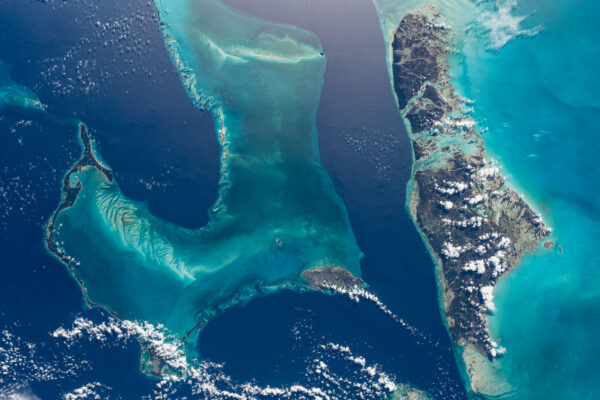 Další z pohledů na ostrovy státu Bahamy. Moře zde hraje barvami. Hlavní město Nassau je na menším protáhlém ostrůvku přibližně uprostřed snímku. Vpravo vidíme ostrovy, které bychom na mapě našli západně od Nassau (snímek má sever dole). Zdroj: flickr.com