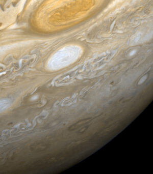 Jupiterova Velká rudá skvrna. Je vidět u horního okraje obrázku.