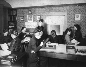 Harvardské počítačky někdy kolem roku 1900. Třetí zleva sedí trochu vzadu s lupou Antonia Maury, Henrietta Swan-Leavitt sedí uprostřed v popředí, za ní stojí Williamina Fleming.