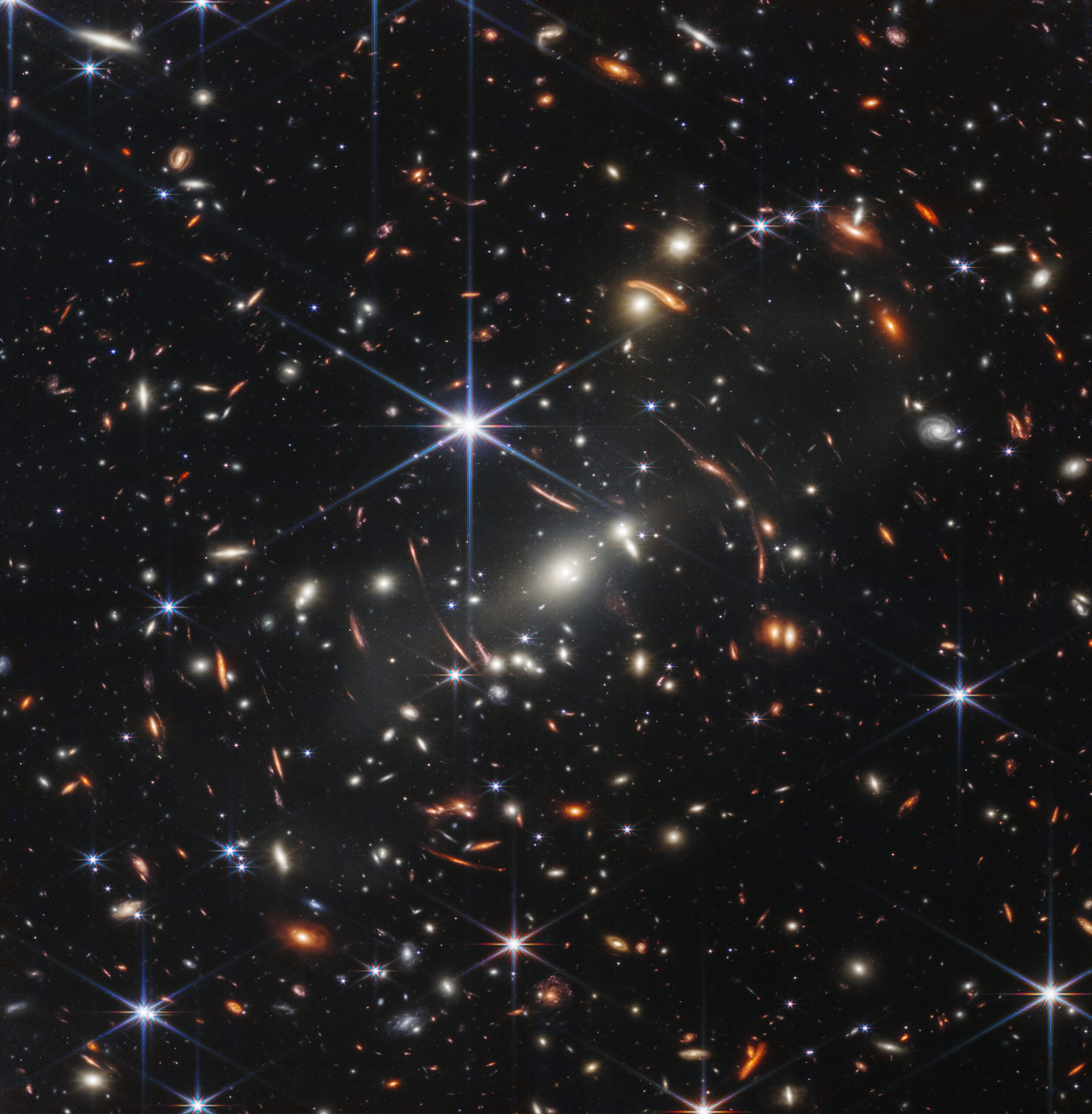 Na snímku je oblast oblohy, jak se vyjádřil Bill Nelson, šéf NASA, velká asi jako zrnko písku, když jej podržíme na natažené ruce. Přesto je zde nepřeberné množství velmi vzdálených galaxií. A gravitace těchto galaxií zobrazuje ještě mnohem starší světlo galaxií za ní. Hvězd, které vznikly krátce po velkém třesku. Credit: NASA/ESA, zdroj: nasa.gov