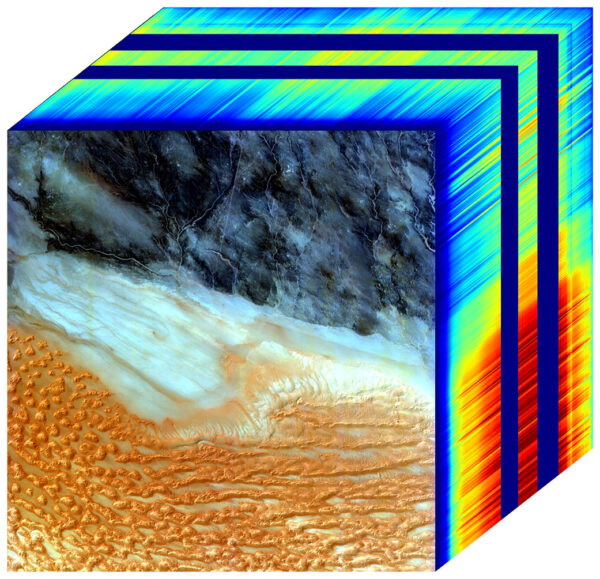 Na přední stěně krychle vidíme obrázek v pravých barvách. Jde o oblast v jihozápadní Libyi, kterou pozoroval přístroj EMIT. Boční stěny ukazují „spektrální otisky prstů“ pro každý bod snímku. Tato datová krychle ukazuje přítomnost kaolinitu, světle zbarveného jílovitého minerálu, který odráží sluneční záření, ale také tmavých minerálů hematitu a goethitu, které pohlcují teplo..