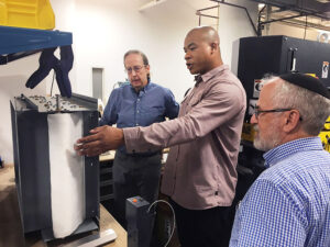 Aaron Wallace (uprostřed) ukazuje porotcům soutěže v Ohiu koncept systému pro filtraci vzduchu (červenec 2022).