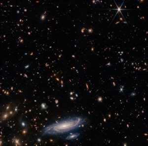 Galaxie LEDA 2046648 dole s tisícem dalších galaxií na pozadí.