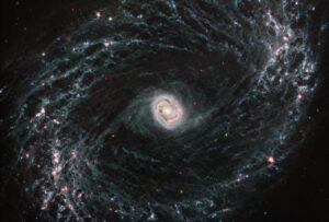 Galaxie NGC 1433 na snímku z přístroje MIRI. Uprostřed vidíme velmi jasné jádro, naopak na okrajích vcelku zřetelnou a výraznou spirální strukturu.