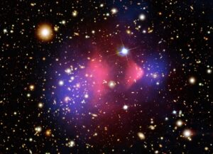 Bullet Cluster. Temná hmota modře na okrajích, rentgenový plyn uprostřed červeně. Tato srážející se kupa galaxií je skvělým důkazem reálné existence temné hmoty. Kromě jiného se zde velmi uplatňuje i slabé gravitační čočkování. 