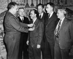 Generál Leslie Groves vyznamenává Enrica Fermiho za jeho přínos projektu Manhattan.