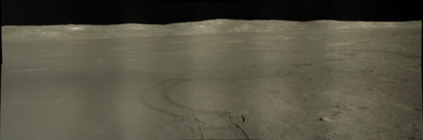 Panoramatický snímek pořízený Nefritovým králíkem 2 zobrazuje jeho vytlačené koleje a vzdálený přistávací modul Čchang-e 4 po několikaletém pobytu na měsíčním povrchu Zdroj: NASA/GSFC/Arizona State University