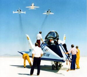 X-24B po přistání. Nad X-24B přelétají doprovodné letouny. T-38 Talon letí uprostřed formace, na křídlech letí F-104