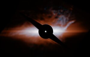 Beta Pictoris na snímku Webbova dalekohledu, přesněji řečeno přístroje MIRI. Rozpoznatelné jsou oba disky kolem hvězdy, vpravo je zřetelný kočičí ohon vybíhající ze sekundárního disku. Černá struktura ve středu snímku je koronograf, který blokuje světlo hvězdy, aby bylo možné vidět její okolí. Samotná Beta Pictoris je lokalizována v samotném středu v místě označeném pěticípou hvězdou. 