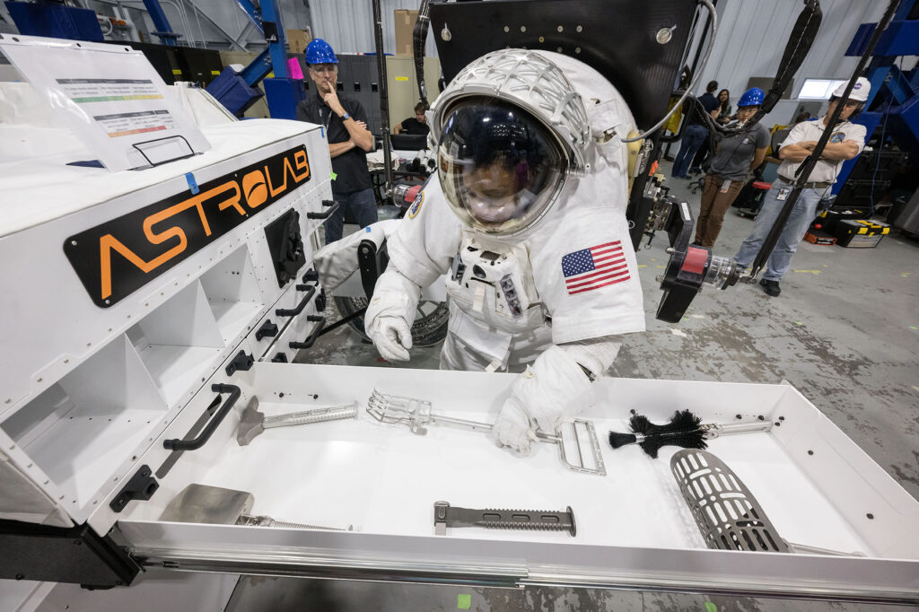 Americká astronautka Jessica Watkins vybírá geologický nástroj z úložiště roveru FLEX od firmy Astrolab.