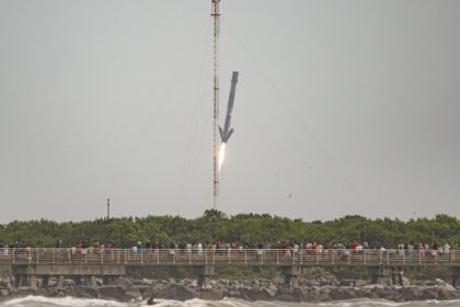 První stupeň B1080 rakety Falcon 9 společnosti SpaceX při přistání na přistávací zóně 1 (LZ-1) na základně Cape Canaveral Space Force Station asi sedm a půl minuty po startu. Snímek byl pořízen v rámci startu mise NG-21.