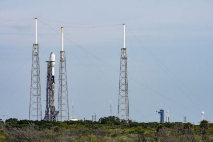 Raketa Falcon 9 (vlevo) stojí na rampě SLC-40 na Cape Canaveral Space Force Station a čeká na start s dvěma internetovými družicemi O3b mPOWER. V pozadí stojí raketa Falcon Heavy na rampě LC-39A a čeká na start mise ViaSat 3 Americas (alias ViaSat-3 F1).