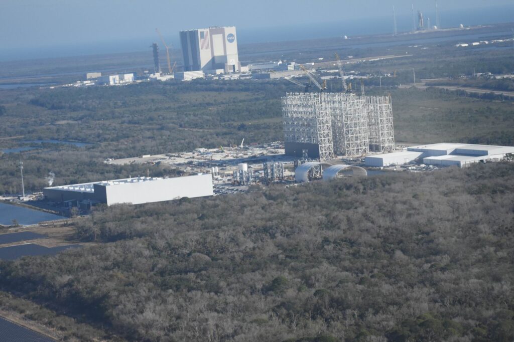 Areál SpaceX, stavba Gigabay, hangár VAB, SLS na rampě...