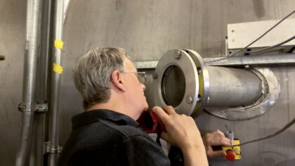 James Polk, vedoucí vědecký pracovník JPL, nahlíží do vakuové komory condensable metal propellant (CoMeT) v laboratoři elektrickýcho pohonů na JPL, kde se v únoru 2026 testoval prototyp vysoce výkonného elektrického pohonu, který vyvinul jeho tým.