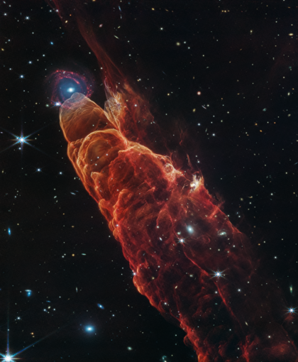 Snímek z dalekohledu JWST ukazuje výron z nově se formující hvězdy, což dalo tomuto objektu Herbig-Haro (HH 49/50) jeho přezdívku „kosmické tornádo“. Tento sloup plynu a prachu vypadá, jako by byl zakončen galaxií, ale ve skutečnosti je galaxie vzdálena od hvězdy světelné roky. Zdroj: NASA, ESA, CSA, STScl